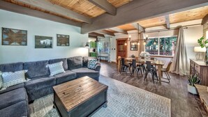 A spacious living area with a wooden ceiling, a gray sofa, a wooden coffee table, and a dining table with chairs. - Mv30 unique Lake Tahoe cabin with great wifi (South Lake Tahoe)