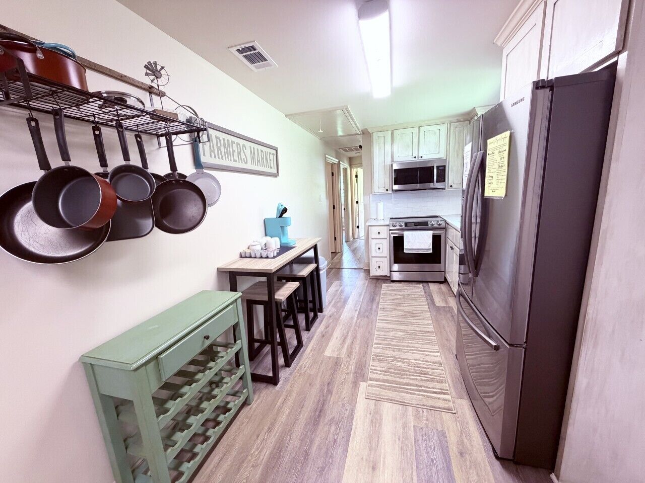 A kitchen with a refrigerator, stove, oven, and hanging pots.