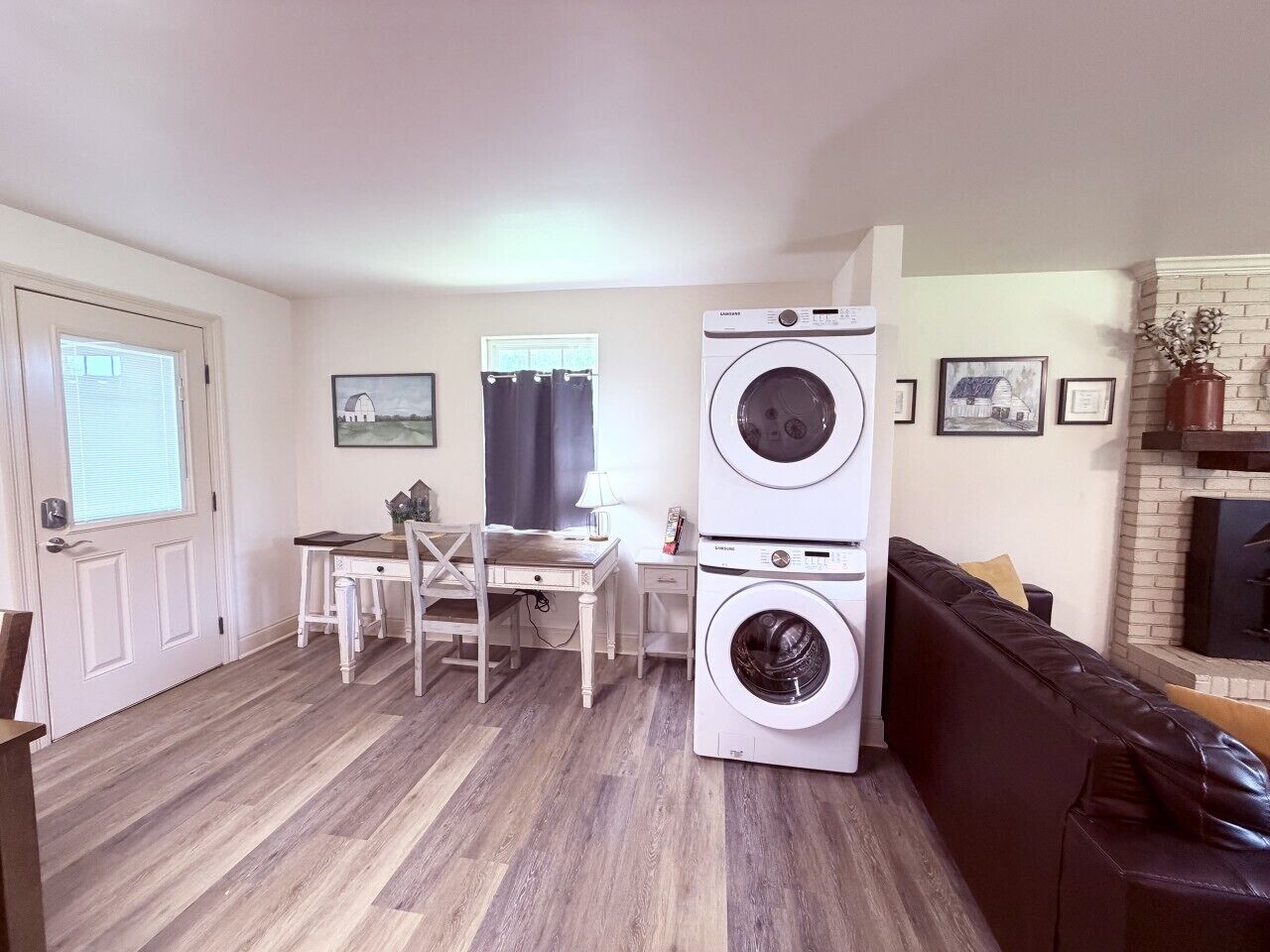 Un espace de vie compact comprenant un coin repas, un canapé, une cheminée et un lave-linge et un sèche-linge superposés.