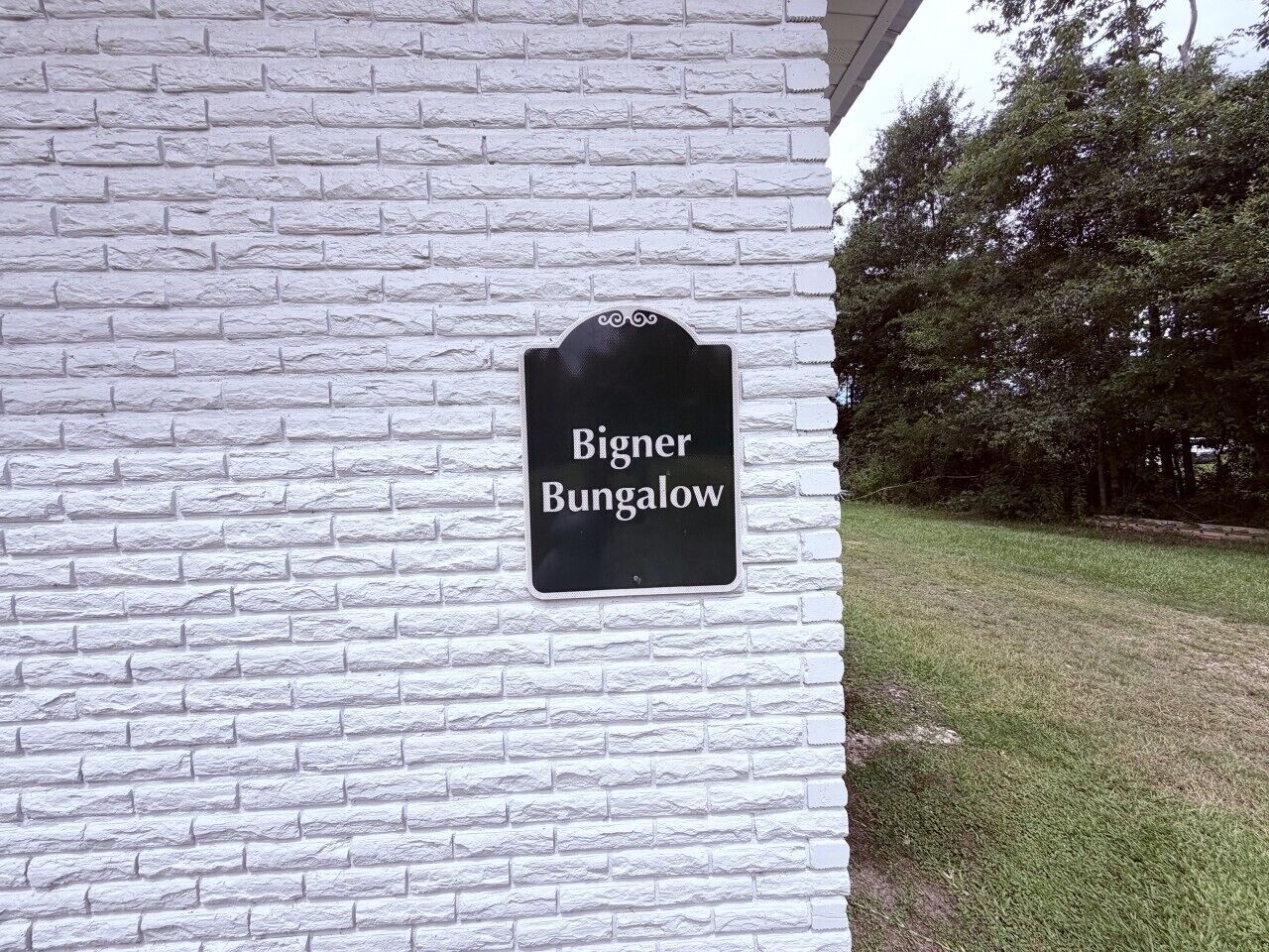 A sign on a white brick wall indicating 'Binger Bungalow.'