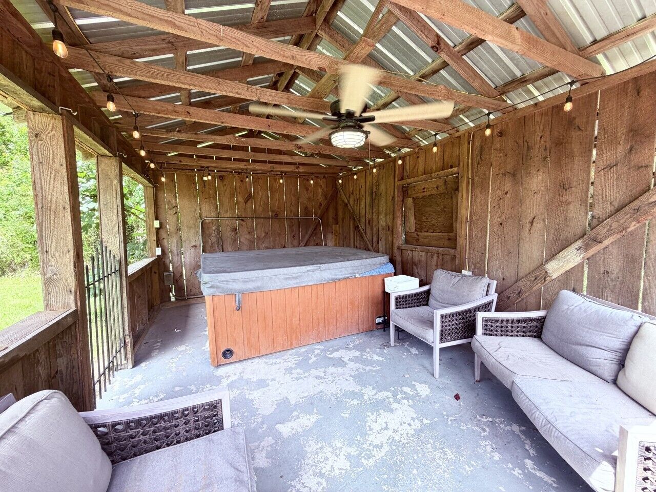 A hot tub area with a ceiling fan, wooden walls, and seating.
