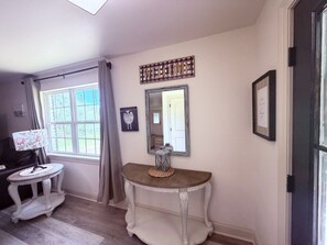 A room with a console table, a mirror, a lamp, and a framed welcome sign. - Farm House stay with soaking tub and hot tub barn (Tickfaw)