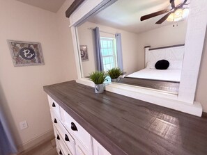 A bedroom with a bed, a dresser, a mirror, and a ceiling fan.