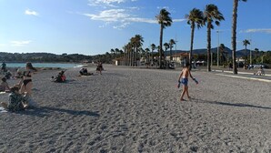 Een strand met palmbomen, mensen die ontspannen en een heldere lucht.