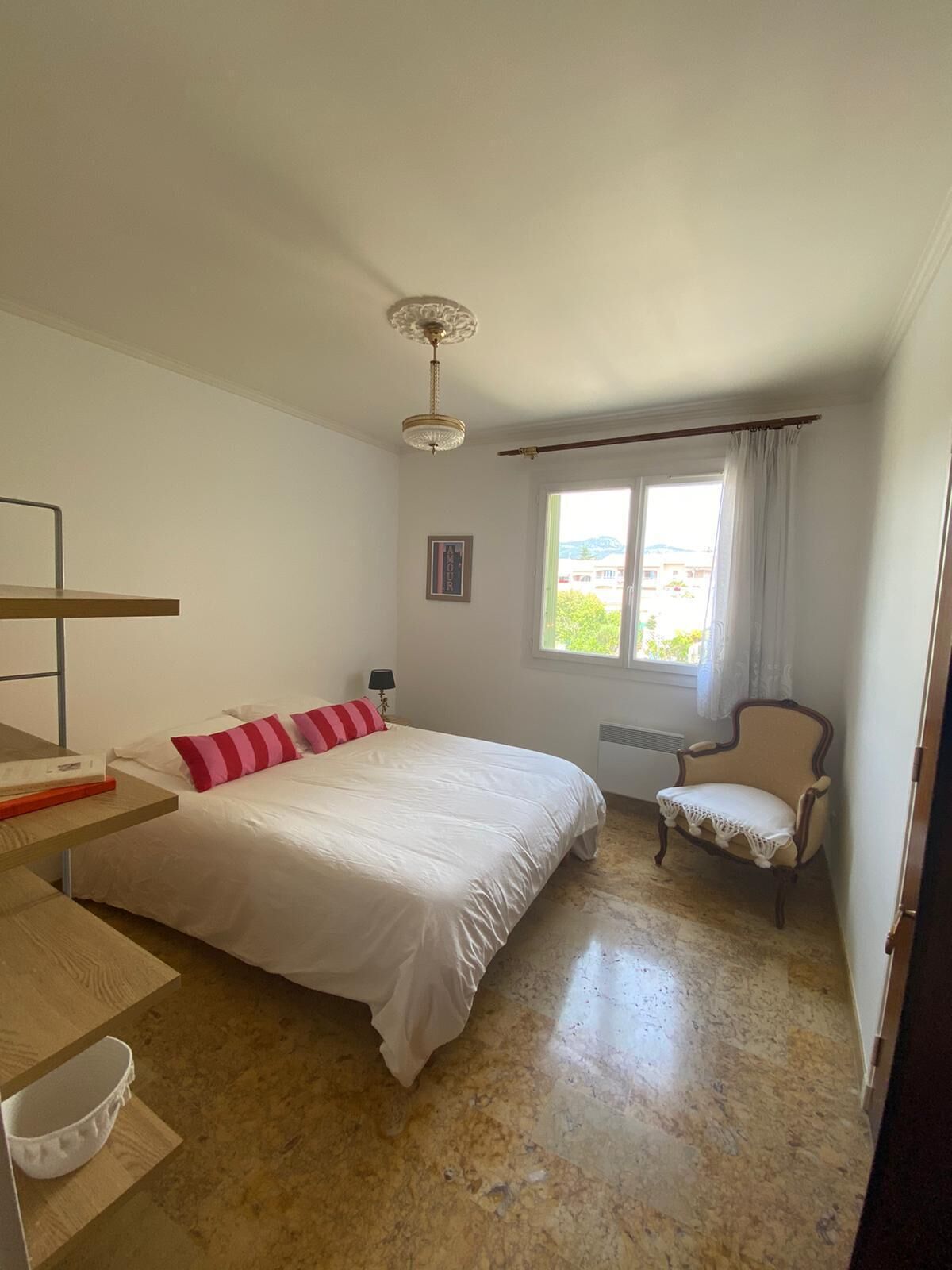 A bedroom with a bed, a chair, a desk, and a window.