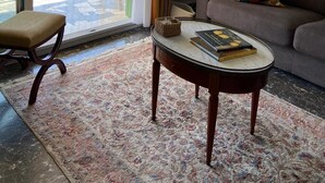 Een woonkamer met een bank, salontafel, stoel en uitzicht op een balkon met een hekwerk en groen.
