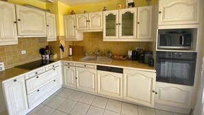 Een keuken met witte kastjes, een spoelbak, een vaatwasser, een magnetron en een oven.