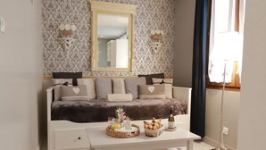 Un salon moderne avec un canapé, une table basse sur laquelle sont disposés des éléments pour le petit-déjeuner, un miroir et un papier peint à motifs.