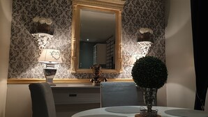 Un coin repas comprenant une table ronde, des chaises, un vase décoratif et des lampes fixées au mur.
