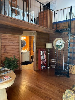 A multi-level wooden interior with a staircase, a bookshelf, and a dining area.