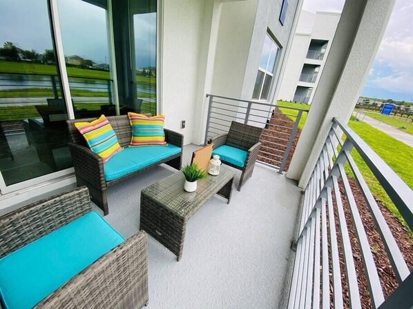 A balcony with wicker furniture, a small table, and a potted plant.
