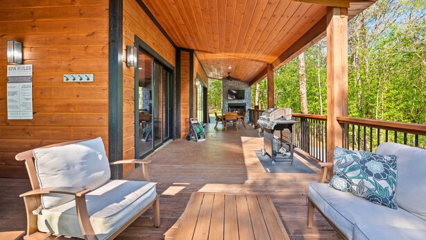 Une terrasse en bois dotée d’un espace couvert, de sièges d’extérieur et d’un barbecue.