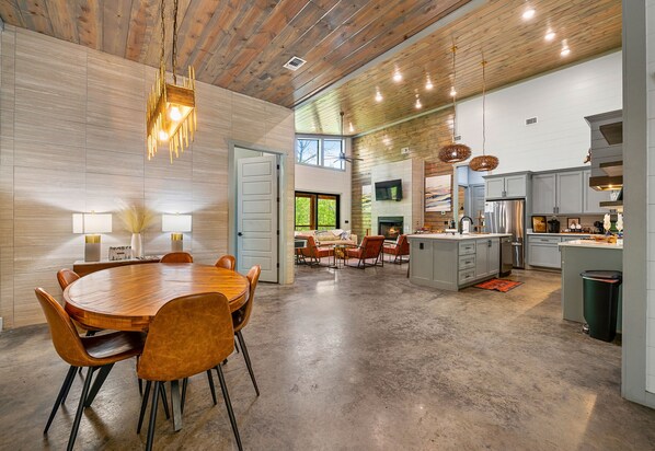 A spacious kitchen with modern appliances, a dining area with a round table, and a living space with a fireplace.