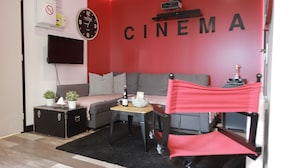 A modern living room with a red accent wall, a sofa, a coffee table, a TV, and a projector. - Cinema apartment with home cinema and garage (Honfleur)