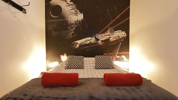A bed with a Star Wars-themed wall art, a pillow, and a blanket. - Cinema apartment with home cinema and garage (Honfleur)
