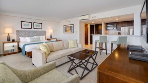 Een hotelkamer met een bed, een slaapbank, een salontafel, een bureau en een kitchenette.