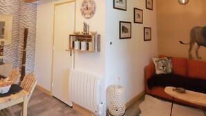 Ein gemütliches Wohnzimmer mit Holzbalken, einem Kamin, einer Couch und einem Essbereich mit Tisch und Stühlen.