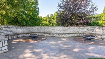 A curved stone wall with two circular water features and a paved area.