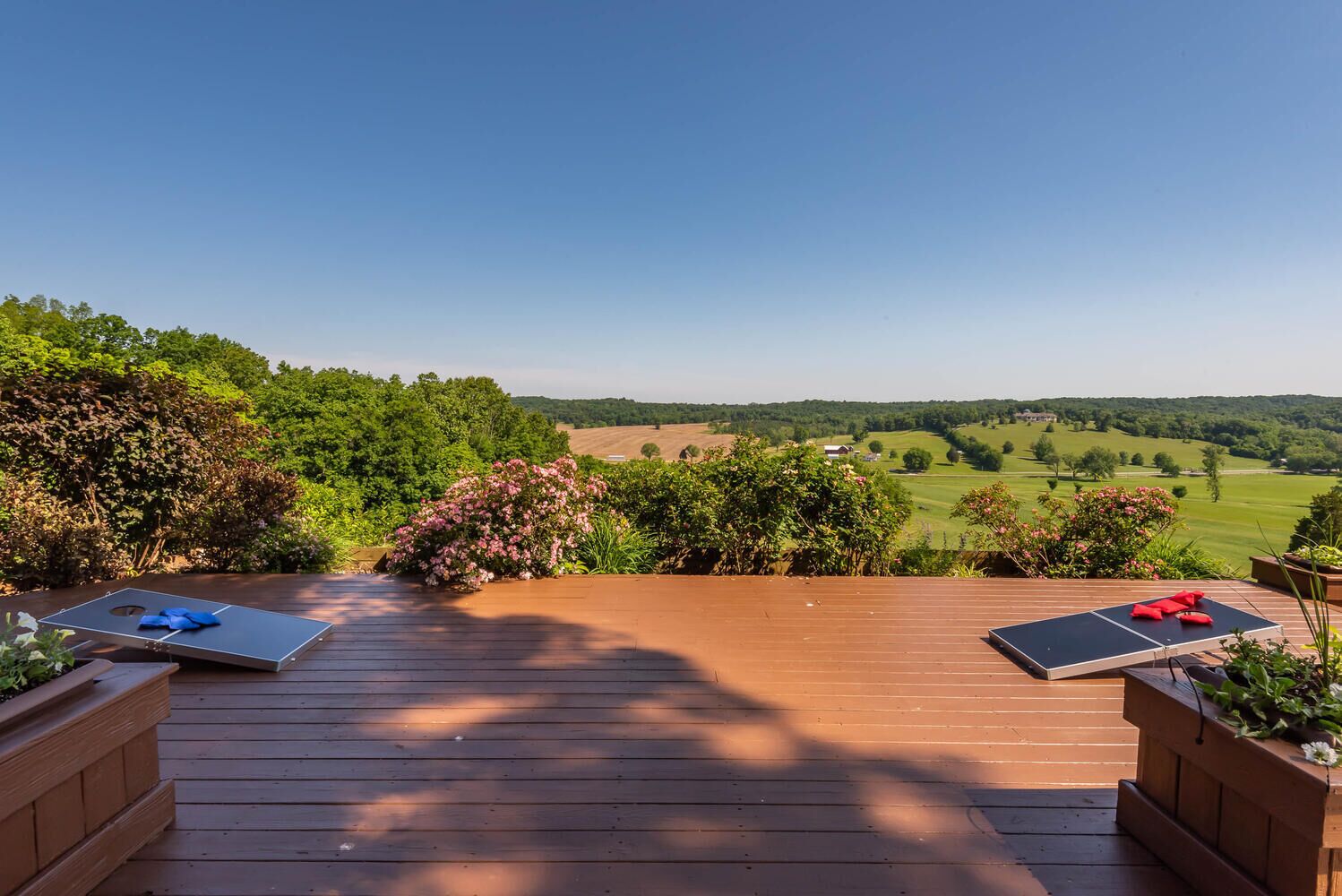 Une terrasse en bois avec deux chaises longues et une vue sur un paysage verdoyant.