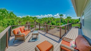 A wooden deck with wicker furniture and a view of lush greenery.