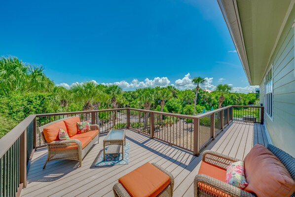 A wooden deck with wicker furniture and a view of lush greenery.