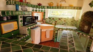A kitchen with green and white checkered tiles, a microwave, a coffee maker, and a window with a view of greenery.