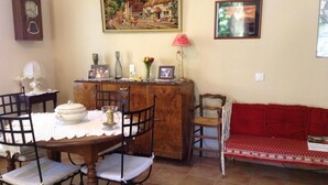 A dining area with a wooden table, chairs, a red sofa, and a painting on the wall.