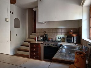 Una cocina equipada con estufa a gas, horno, microondas, tostadora y pileta.
