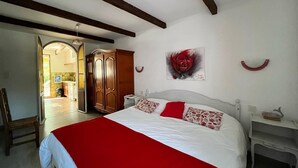 A bedroom with a bed, a red and white bedspread, a wooden wardrobe, a painting of a rose, and a white bedside table. - Les Roses Rouges - SIX Fours LES Plages (SIX FOURS LES PLAGES)