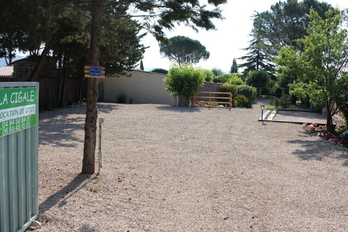 A gravel parking area with a sign indicating 'LA CIGALE' and 'LOCATION DE GITES'.