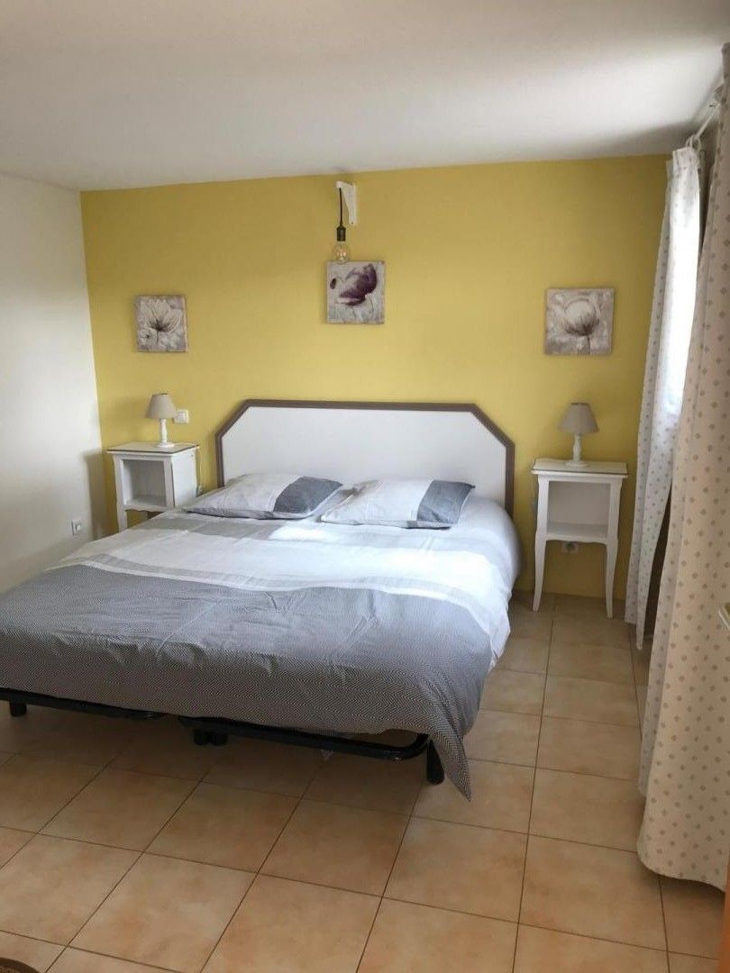 Een slaapkamer met een bed, twee nachtkastjes en twee wandlampen.