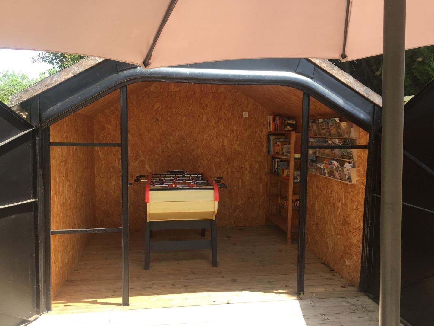 A cozy, enclosed space with a foosball table and a bookshelf filled with books.
