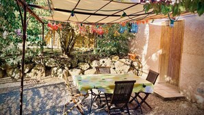An outdoor patio with a table and chairs, a stone wall, and a pergola with string lights.