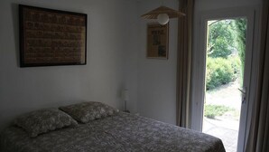Un dormitorio con una cama, un cuadro en la pared y una puerta que da a un espacio al aire libre.