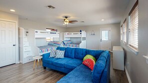 A bedroom with bunk beds, a blue sofa, and a ceiling fan.