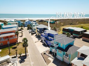 A coastal residential area with colorful houses, a beach, and a clear sky.