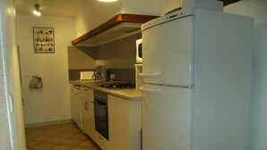 A compact kitchen with a white refrigerator, stove, oven, and microwave.