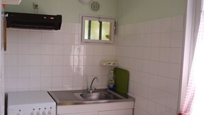 Uma cozinha compacta com fogão, pia e janela.
