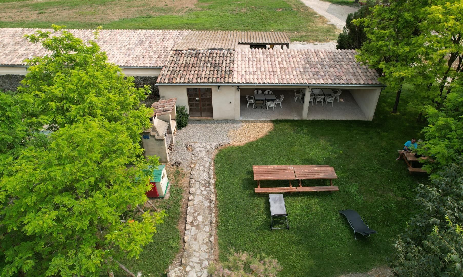 Une villa avec un toit en tuiles, un patio agrémenté de mobilier d’extérieur et un chemin de pierre menant à l’entrée.