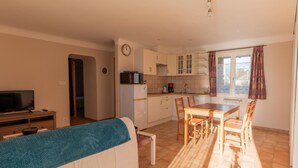 Un espacio habitable compacto con kitchenette, comedor y televisor en la sala.