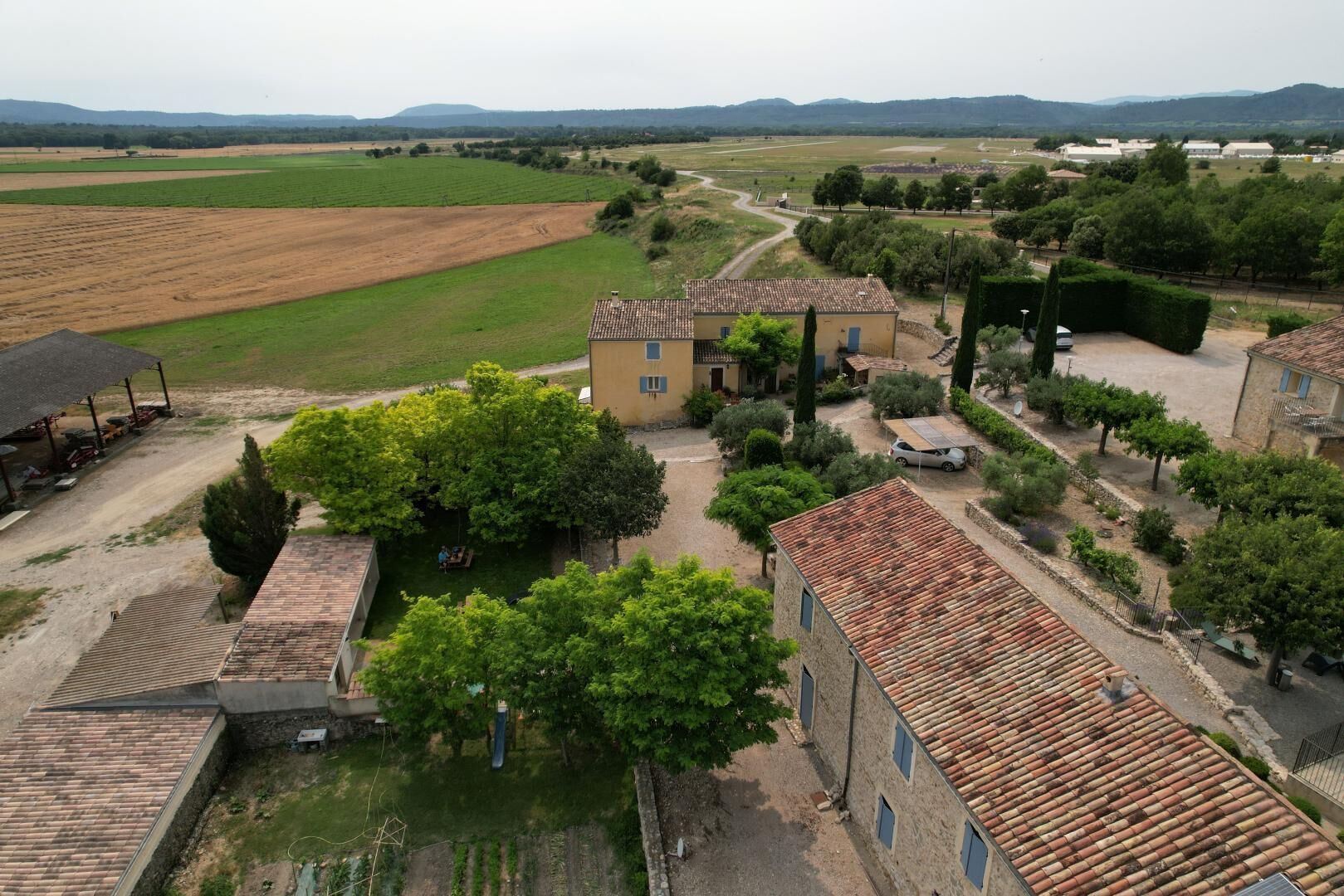 Un pueblo rural con edificios tradicionales, un camino de tierra y campos circundantes.