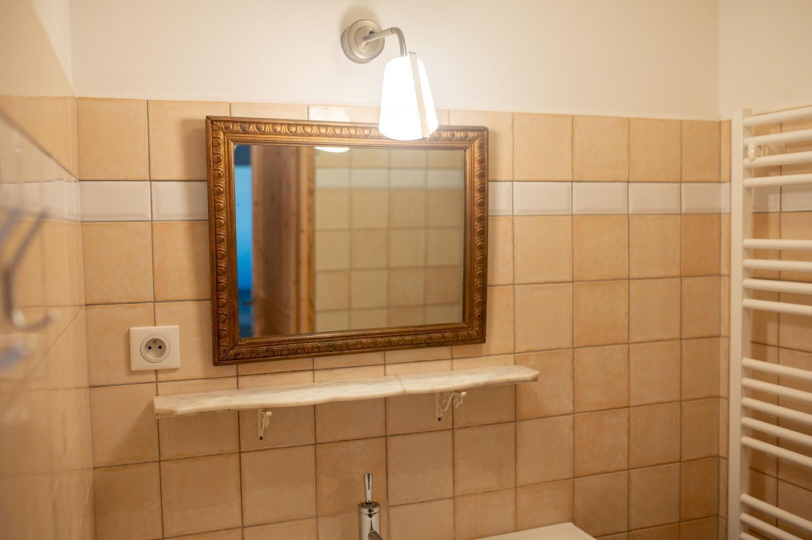 Une salle de bain avec un miroir, un porte-serviettes et un luminaire.