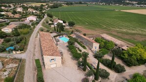 Una propiedad campestre con piscina, edificios de piedra y campos aledaños.
