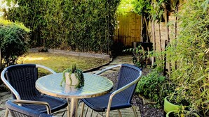 A wooden deck with wicker chairs and a round table, surrounded by lush greenery and a wooden fence. - Lake house - 3 bedroom woking (Woking)