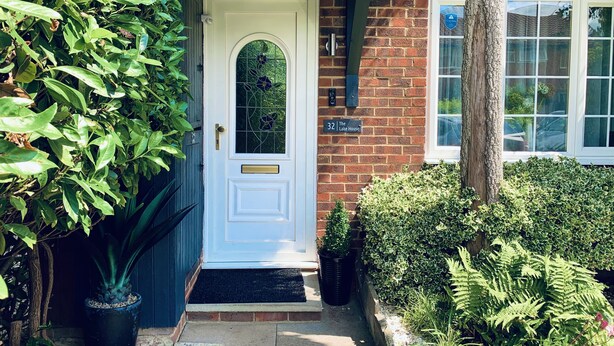 A brick house with a white door, a mailbox, and a window with a blue plaque. - Lake house - 3 bedroom woking (Woking)