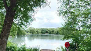A serene lakeside view with a dock, lush greenery, and a red stop sign. - Lake house - 3 bedroom woking (Woking)