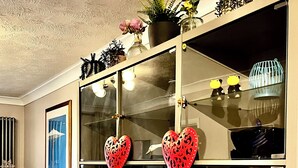 A glass-fronted cabinet with decorative items, a framed picture, and a vase with flowers. - Lake house - 3 bedroom woking (Woking)