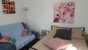 Une chambre à coucher avec un lit, un canapé bleu et une table de chevet avec une lampe.