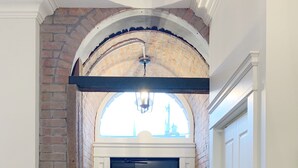 A hallway with a brick wall, a black door, and a white door. - Downtown Heritage Condo (Charlottetown)