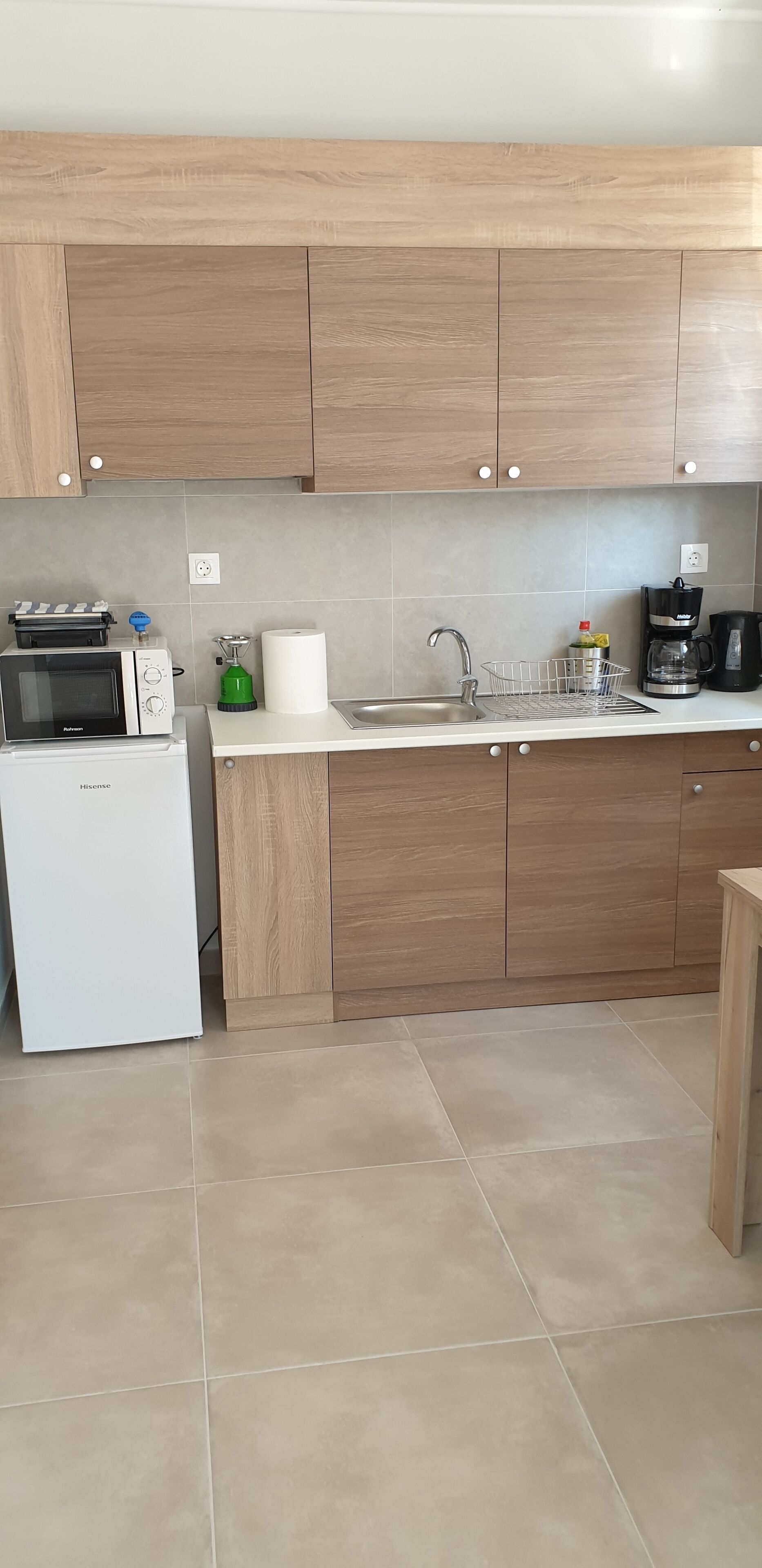 Una cocina moderna con armarios de madera, un refrigerador blanco, un microondas, una cafetera y un lavamanos.